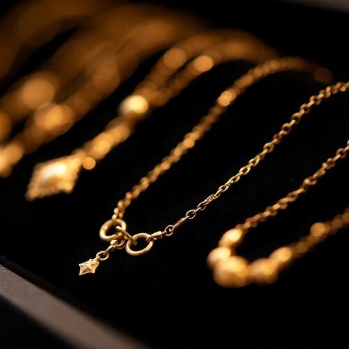 Primo piano di diverse collane d'oro, con catenine sottili e pendenti, su una superficie scura.