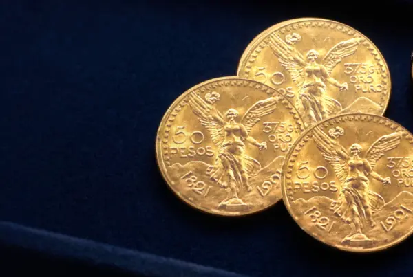 Tre monete da 50 pesos messicani in oro (Centenario) su un vassoio di velluto blu con lente da gioielliere